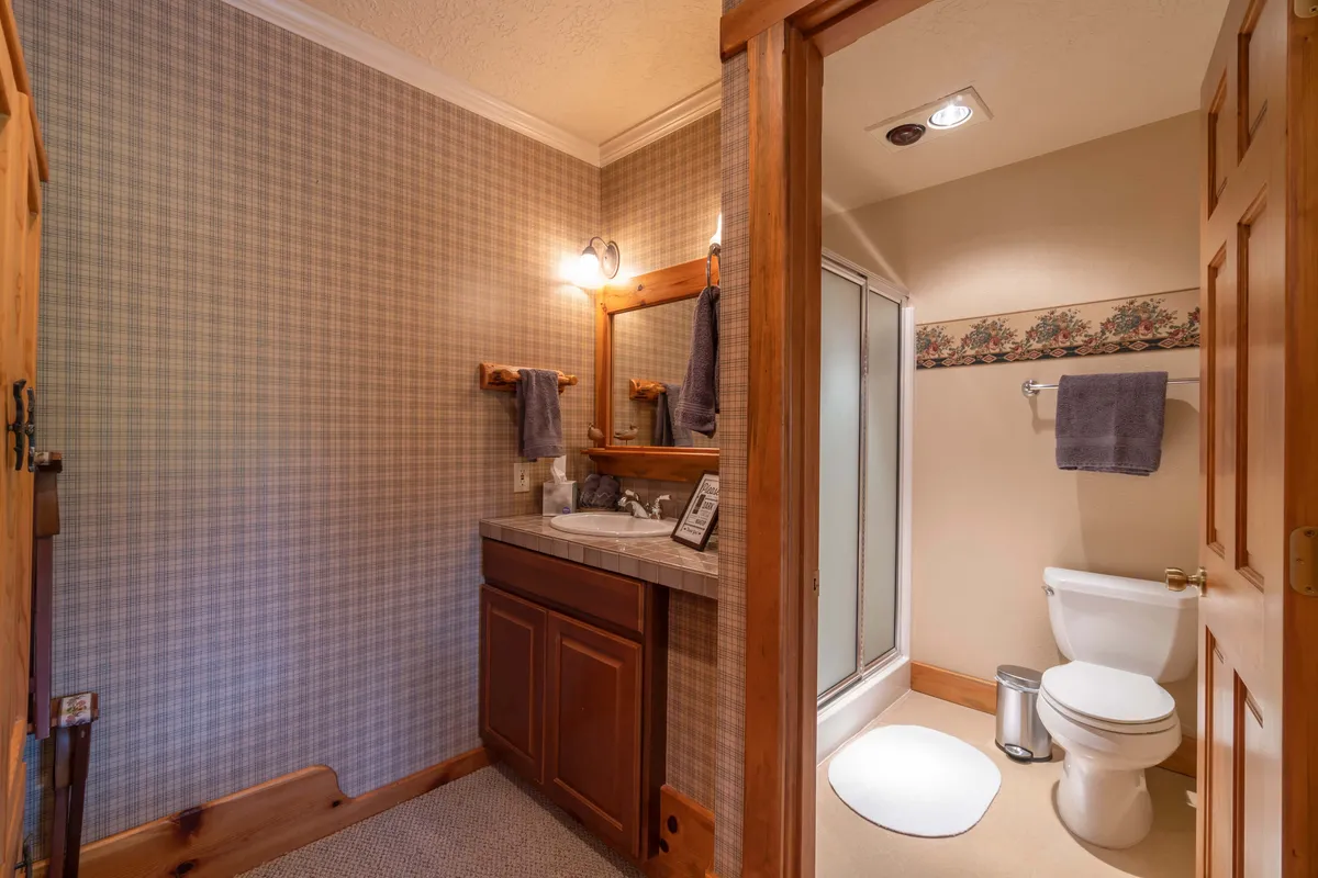 A cozy bathroom with a wooden vanity, sink, shower enclosure, and toilet, designed for comfort and privacy. The setting suggests a space for relaxation and refreshing routines.