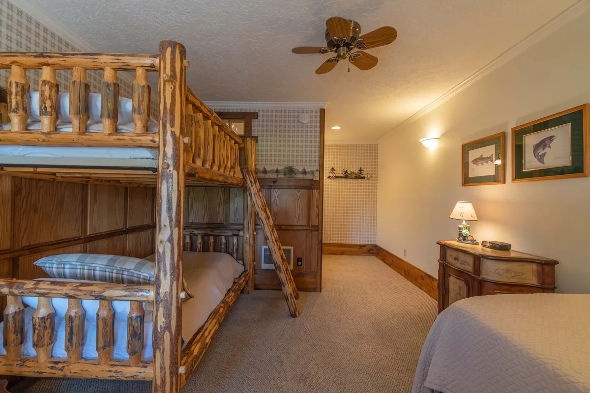 A cozy room featuring a sturdy bunk bed, wooden furniture, and playful wall art. The scene evokes a sense of fun and togetherness, ideal for families or groups with children to enjoy close moments and build memories.